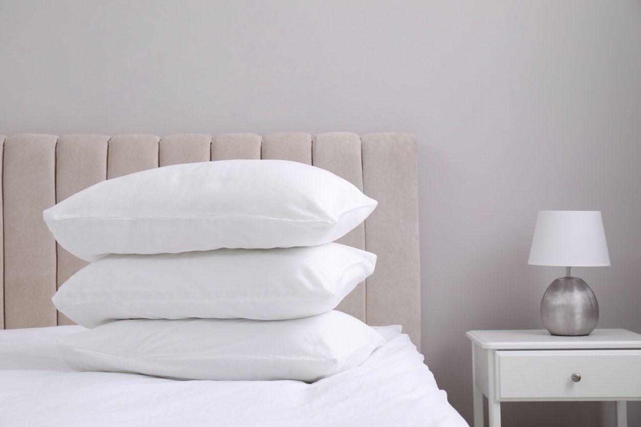 White soft pillows on bed and lamp in room hemstädning